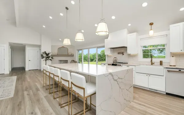 Renovated white kitchen with a marble island and pendant lights