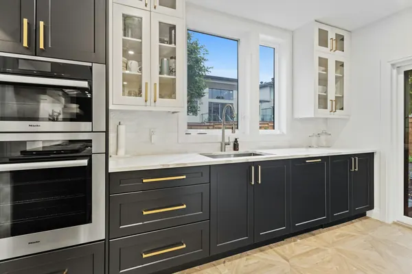 Kitchen with dark shaker cabinets, brass handles and a built-in oven tower