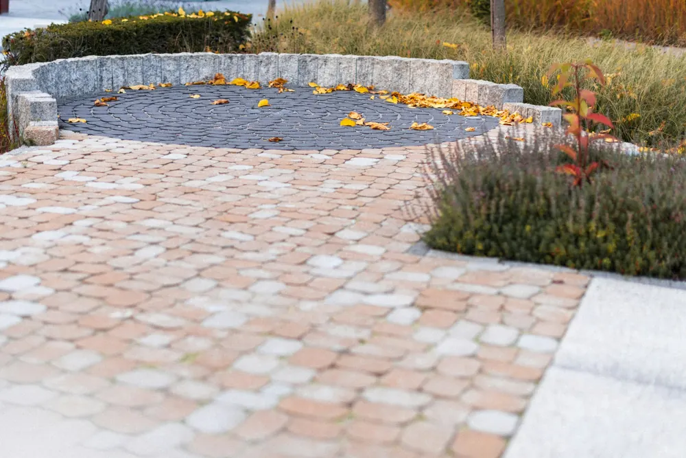 Curved garden path in pale cobbled pavers around a stone circle